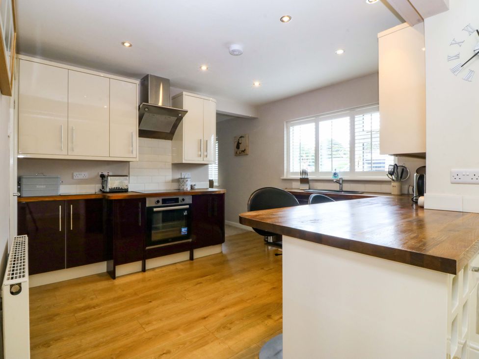 A kitchen with cabinets, stove, and sink at 5 Ger Afon in Llanbedrog