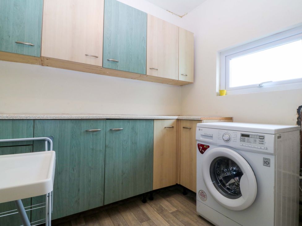 A laundry room with cabinets and a washing machine at 5 Ger Afon Llanbedrog