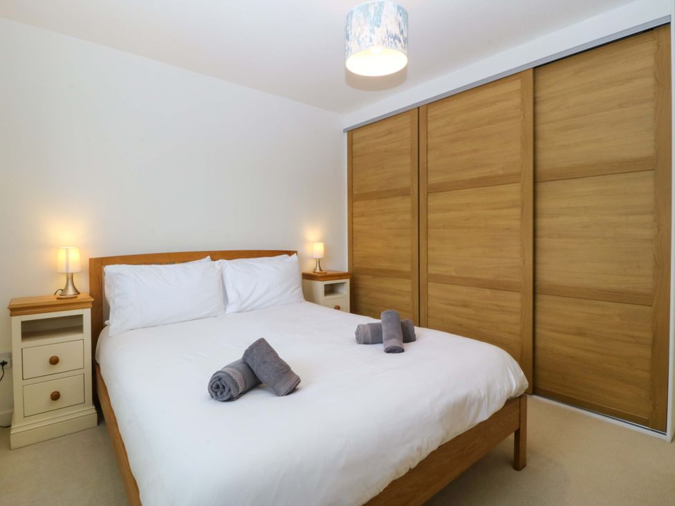 A bedroom with a bed, nightstands and lamps at 5 Ger Afon in Llanbedrog