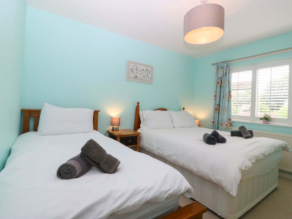 A bedroom with two beds and bedside tables at 5 Ger Afon in Llanbedrog