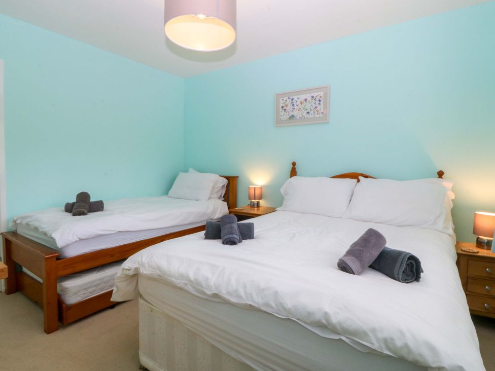 A bedroom with two beds and nightstands at 5 Ger Afon Llanbedrog
