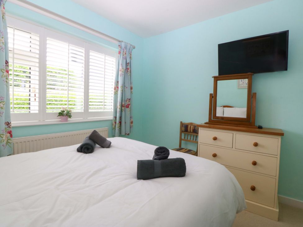 A bedroom with a bed and dresser at 5 Ger Afon in Llanbedrog