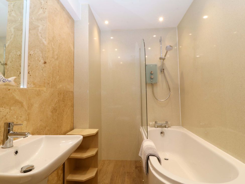 A bathroom with a bathtub, sink, and shower at 5 Ger Afon in Llanbedrog