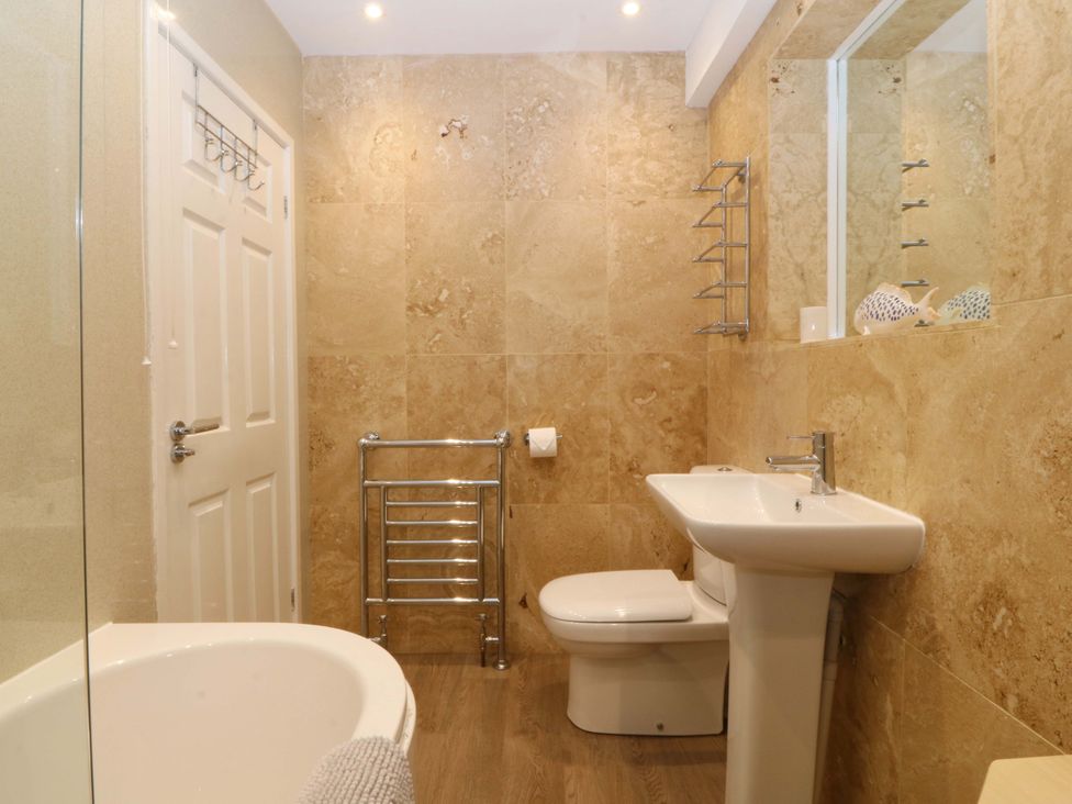 A bathroom with a bathtub, toilet, and sink at 5 Ger Afon in Llanbedrog