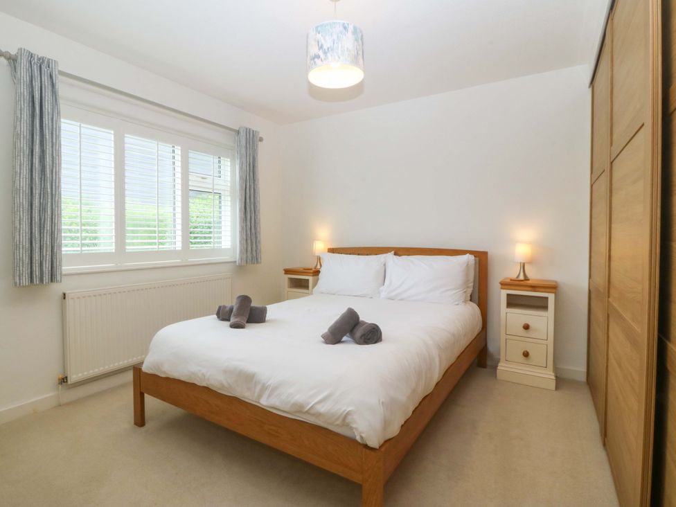 A bedroom with a bed and nightstand at 5 Ger Afon in Llanbedrog