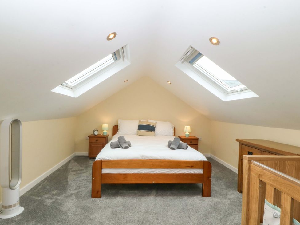 A bedroom with a bed and bedside tables at 5 Ger Afon in Llanbedrog