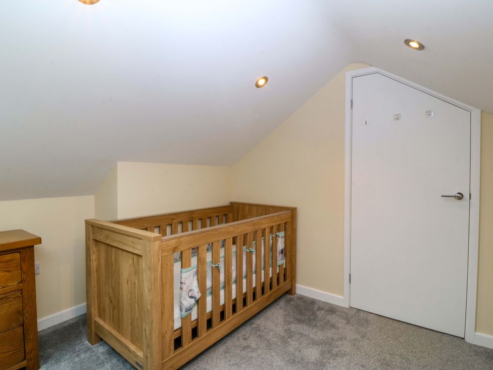 A nursery with a crib and a drawer at 5 Ger Afon in Llanbedrog