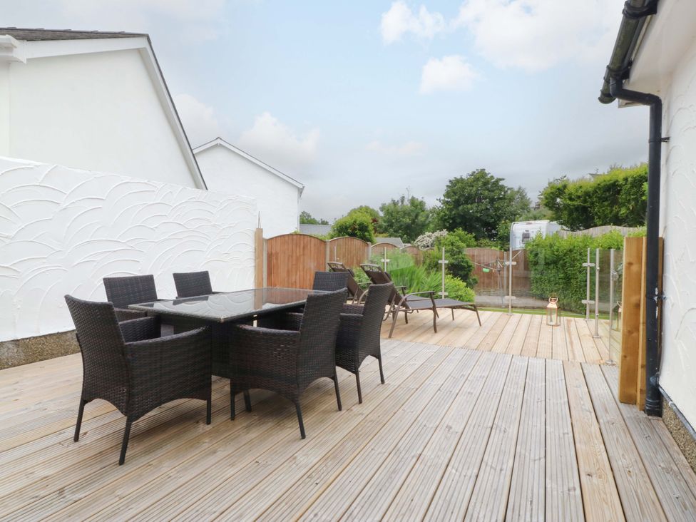 An outdoor area with a table and chairs at 5 Ger Afon in Llanbedrog