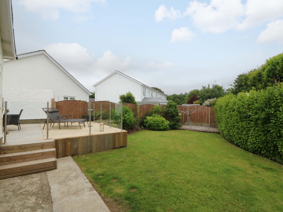 A garden with decking and chairs at 5 Ger Afon Llanbedrog