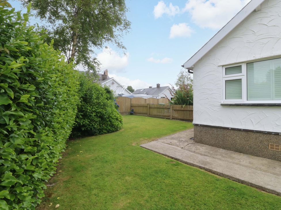 A garden area with grass and a fence at 5 Ger Afon in Llanbedrog