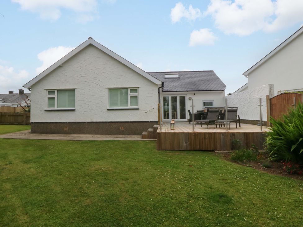 A house with a deck and grass area at 5 Ger Afon in Llanbedrog