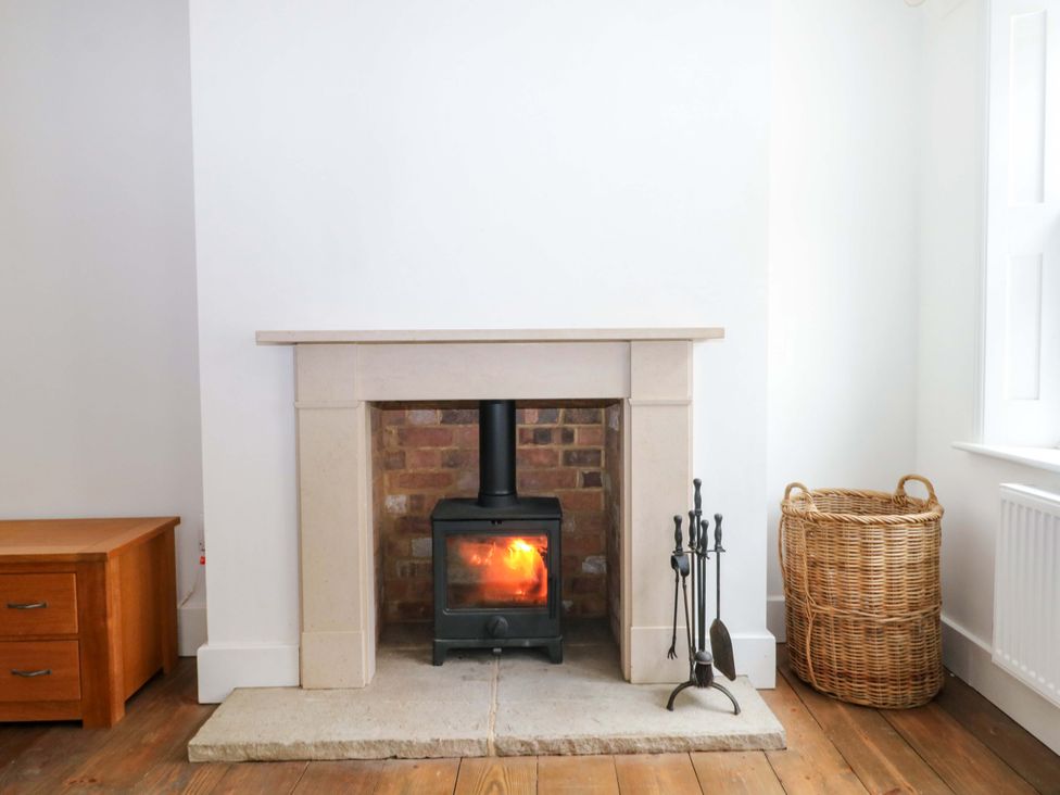 A living room with a fireplace and wooden cabinet at 19 Queen Street in Emsworth