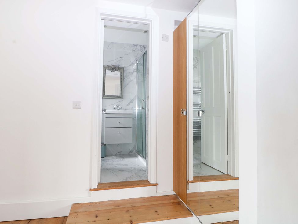 A bathroom with a mirror and door at 19 Queen Street Emsworth