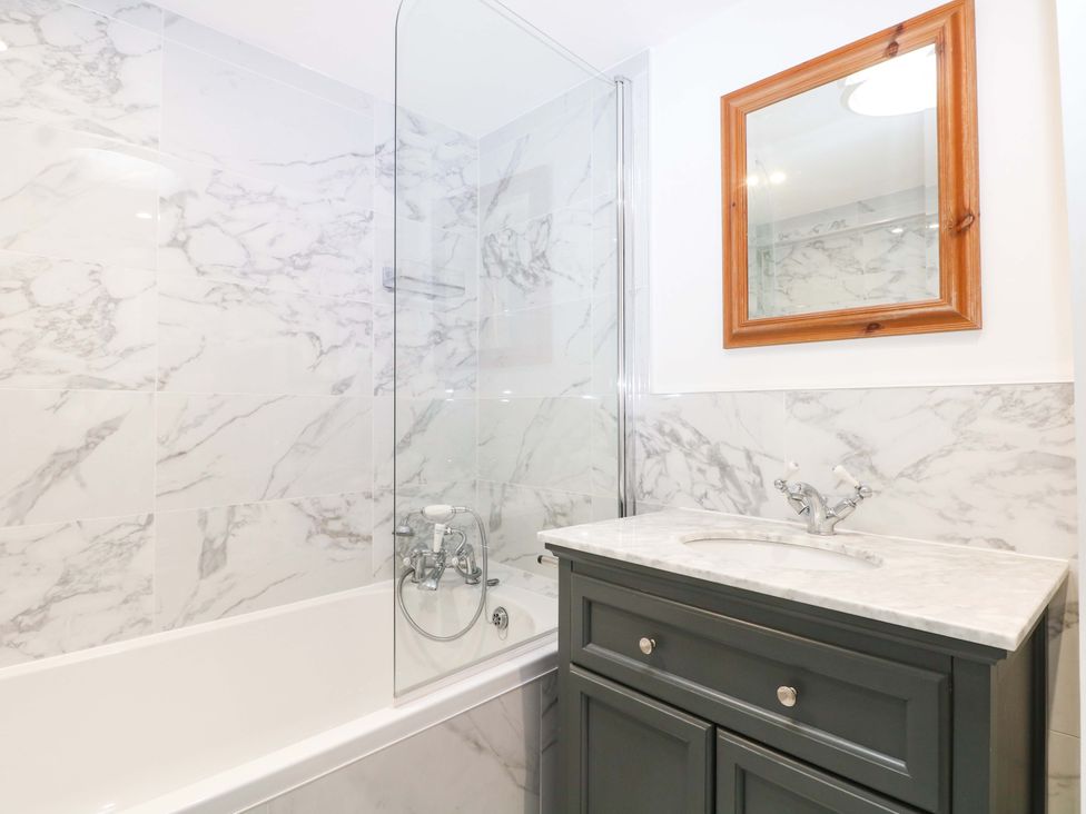 A bathroom with a bathtub, shower, mirror, and sink at 19 Queen Street in Emsworth