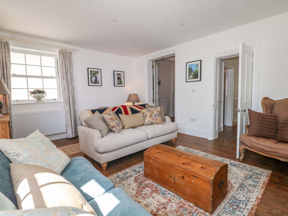 A living room with a sofa, armchair, coffee table, and rugs at 19 Queen Street in Emsworth