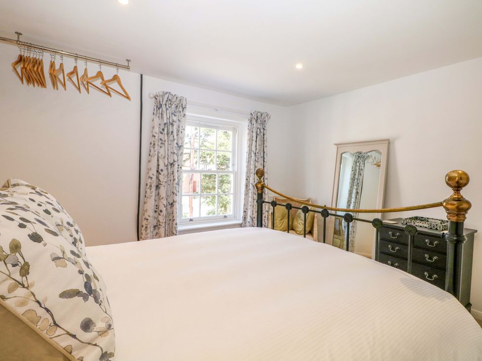 A bedroom featuring a bed with hangers and a mirror at 19 Queen Street Emsworth