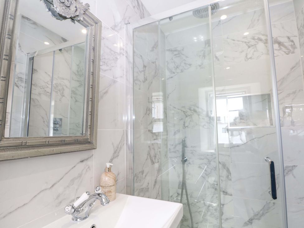 A shower enclosure with a sink and mirror at 19 Queen Street in Emsworth