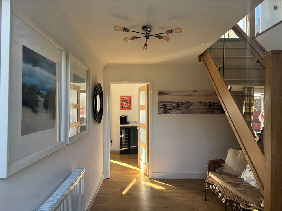A hallway with a staircase and framed pictures at Seaview in Pakefield