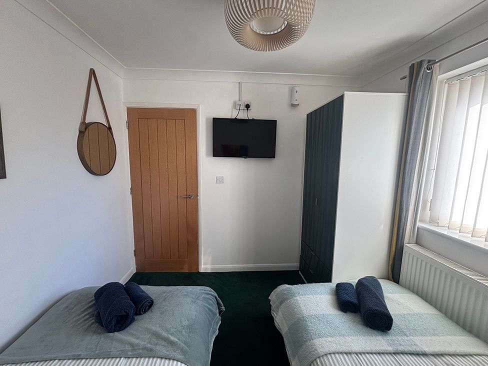 A bedroom with two beds, a wardrobe, and a television at Seaview in Pakefield