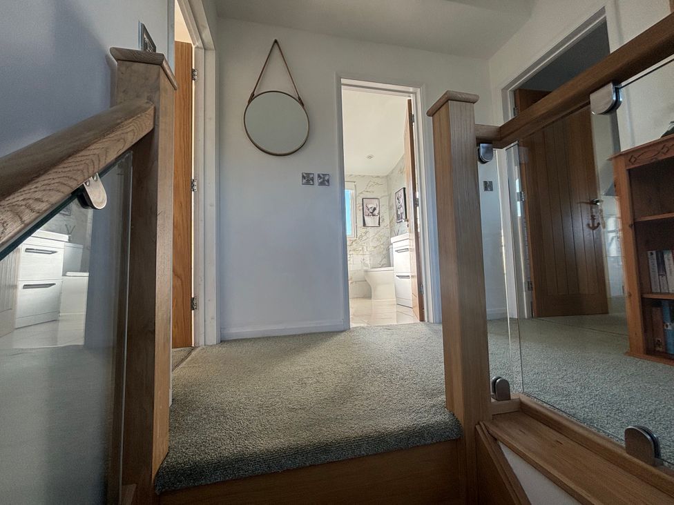 A hallway with a staircase and a mirror at Seaview in Pakefield