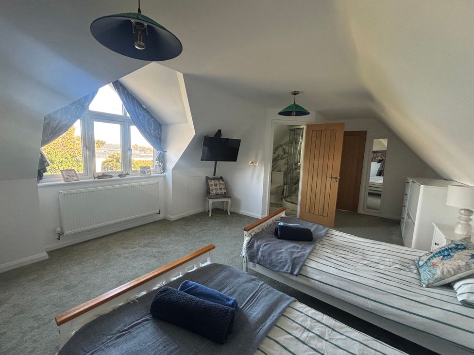 A bedroom with twin beds and a wall-mounted TV at Seaview in Pakefield
