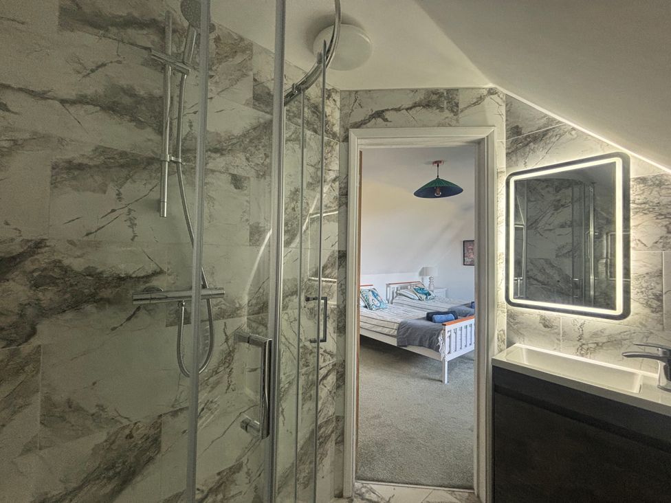 A bathroom with a shower and mirror leading to a bedroom at Seaview in Pakefield