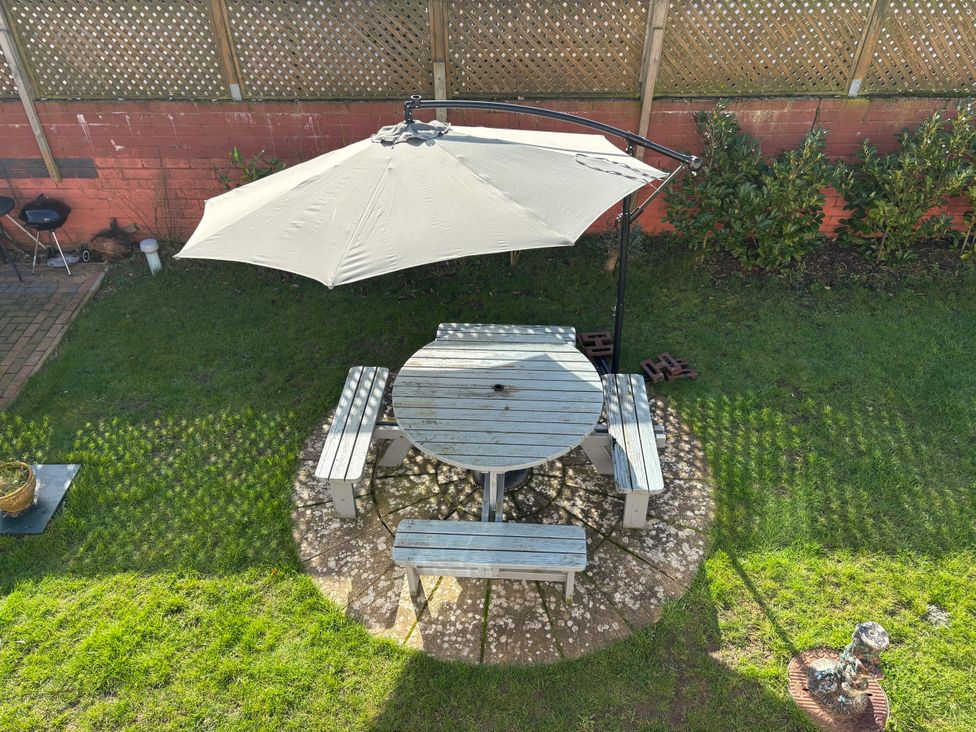A garden with a table and benches under an umbrella at Seaview in Pakefield