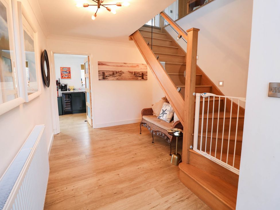 A hallway with a staircase and a bench at Seaview in Pakefield