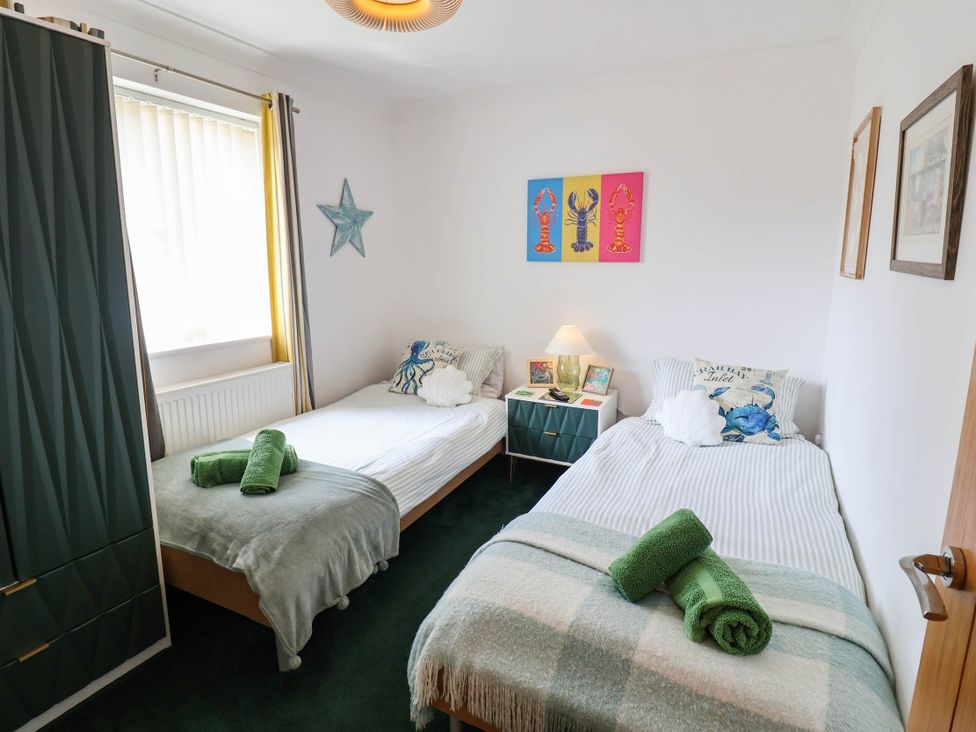 A bedroom with two beds and a table at Seaview in Pakefield