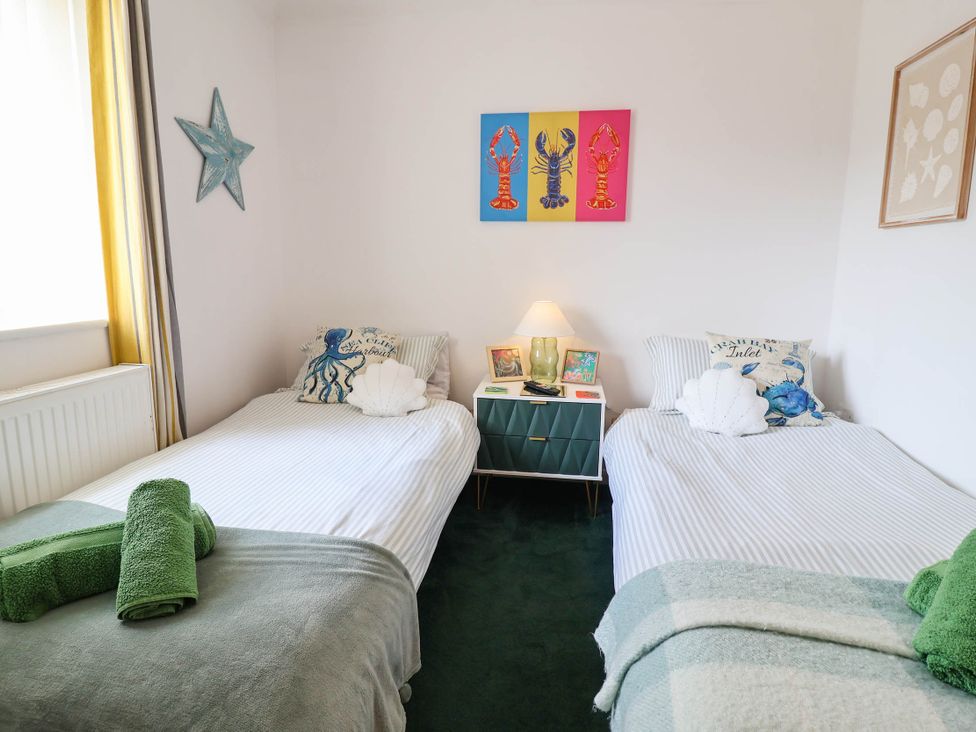A bedroom with two beds and a bedside table at Seaview in Pakefield