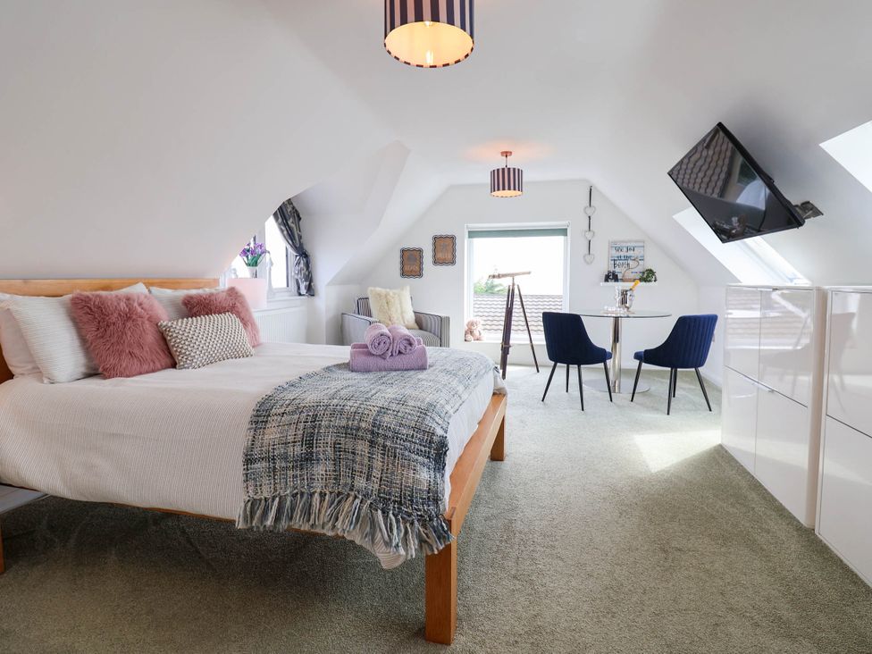 A bedroom with a bed and seating area at Seaview in Pakefield