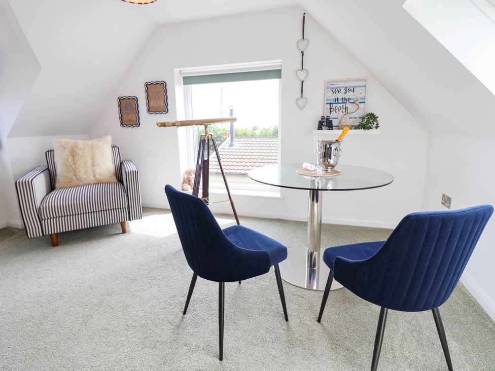 An attic room with a glass table and chairs at Seaview in Pakefield