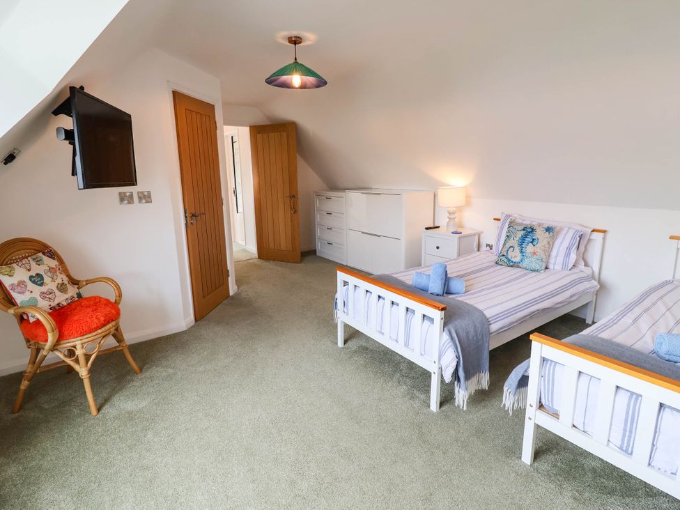 A bedroom with two beds and a chair at Seaview in Pakefield