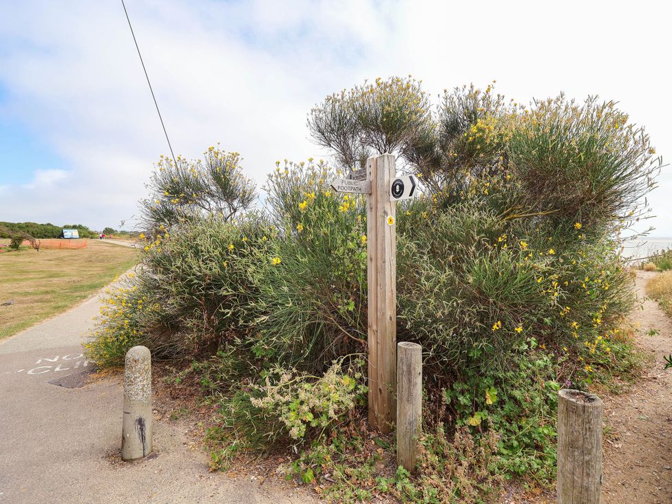 A footpath sign near bushes and a path at Seaview in Pakefield