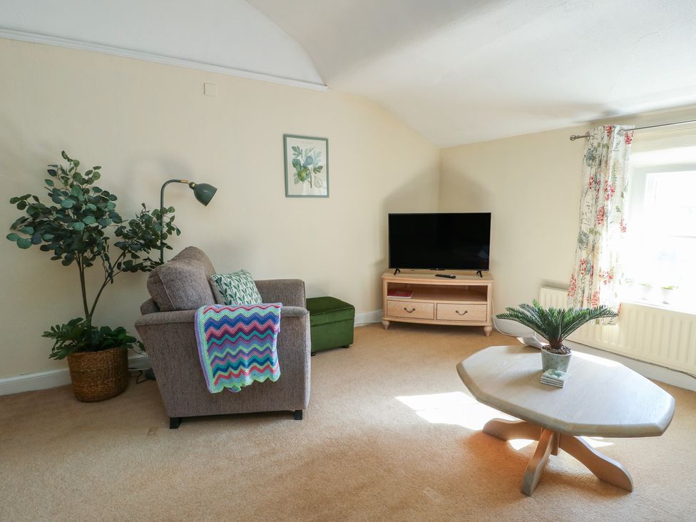A living room with an armchair and television at Castle Gardens Apartment Beaumaris