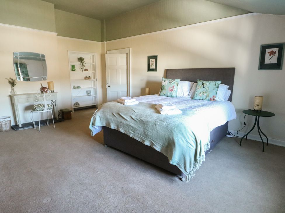 A bedroom with a bed and shelves at Castle Gardens Apartment Beaumaris