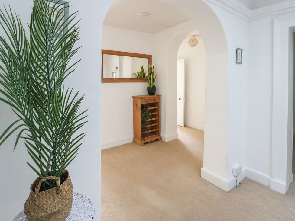 A hallway with a mirror and a wood cabinet at Castle Gardens Apartment Beaumaris
