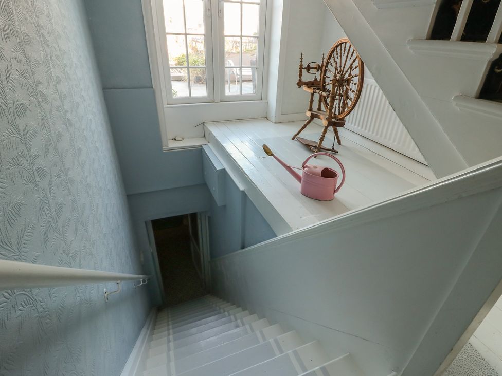 A staircase with a spinning wheel and a watering can at Castle Gardens Apartment Beaumaris