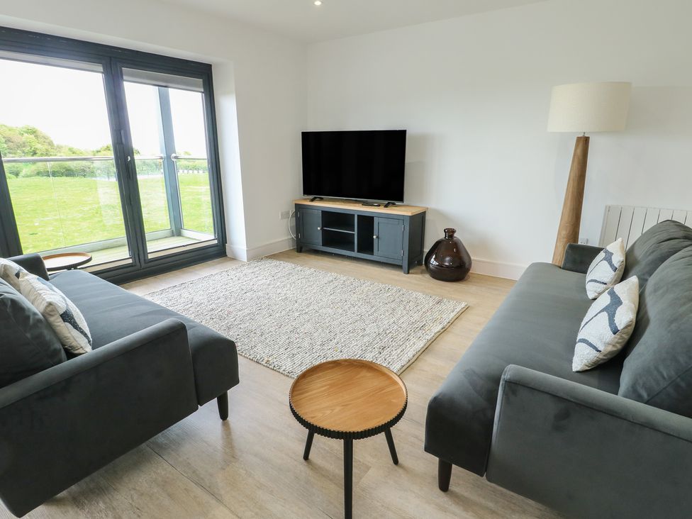 A living room with a television and seating arrangements at Glynllifon 5 Marian-glas near Benllech