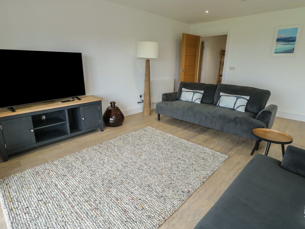 A living room with a TV and sofa at Glynllifon 5 Marian-glas near Benllech