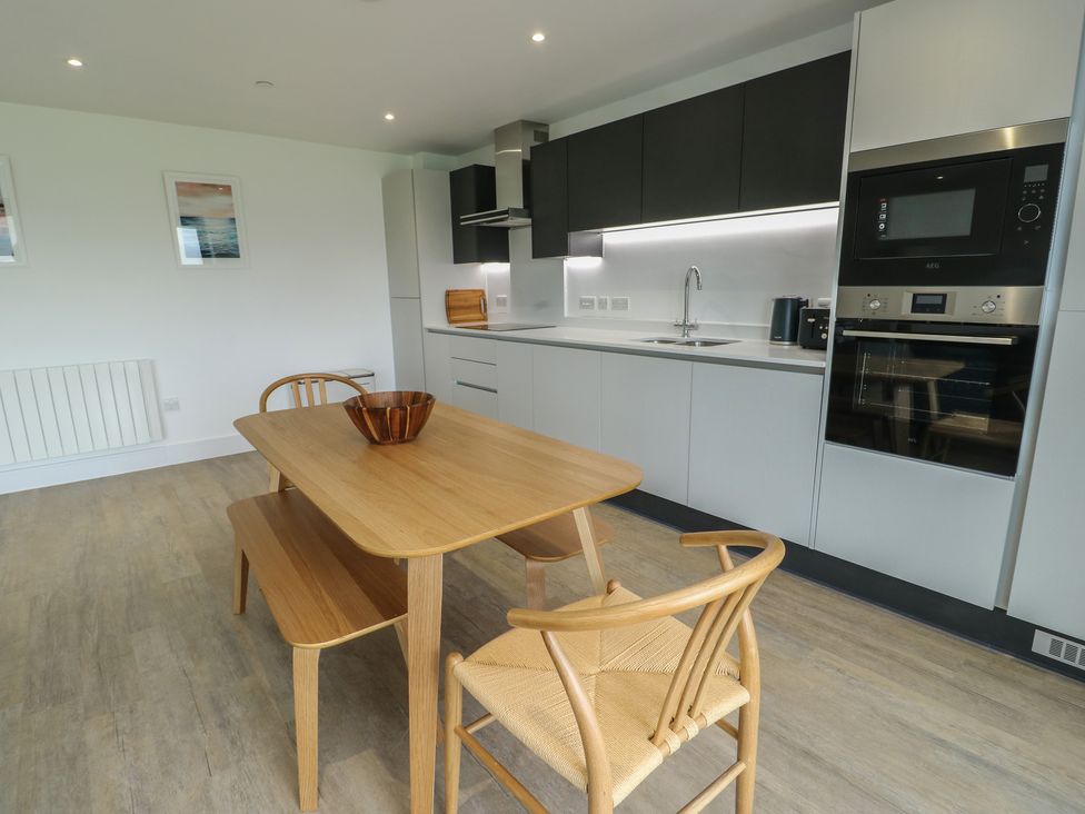 A kitchen with a dining table and chairs at Glynllifon 5 Marian-glas near Benllech