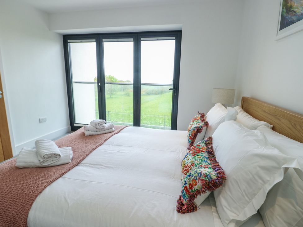 A bedroom with a bed and windows at Glynllifon 5 Marian-glas near Benllech