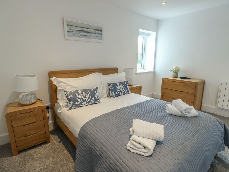 A bedroom with a bed and nightstands at Glynllifon 5 Marian-glas near Benllech