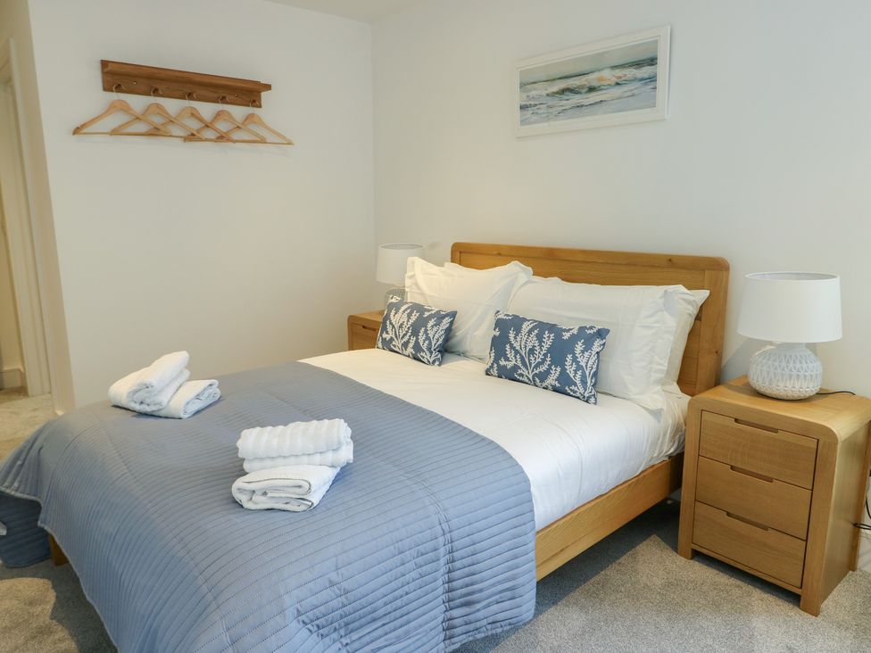 A bedroom with a bed, nightstand, and lamp at Glynllifon 5 Marian-glas near Benllech