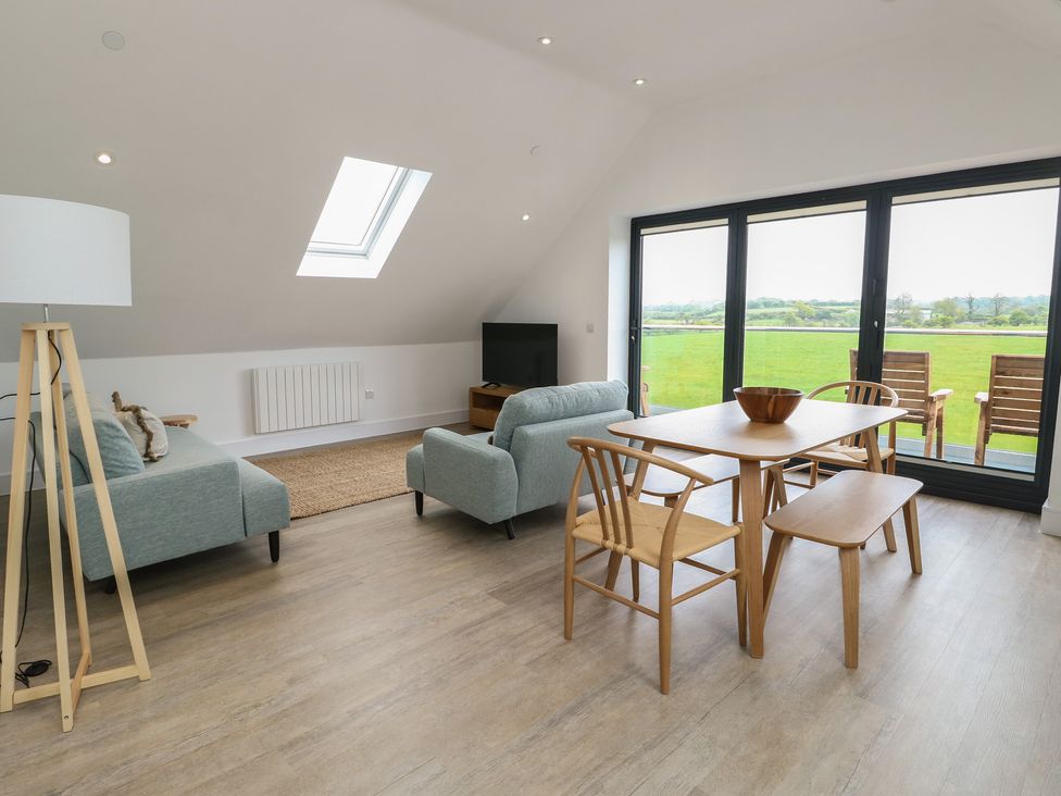 A living room with a sofa and dining table at Glynllifon 7 Marian-glas near Benllech