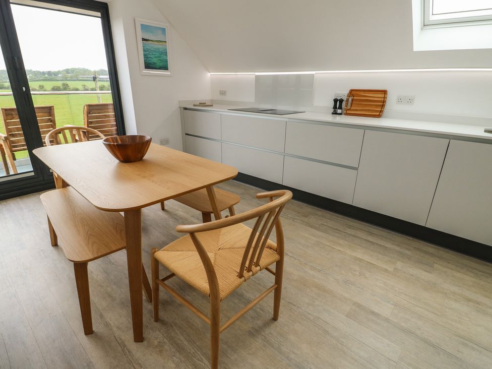 A kitchen with a table and chairs at Glynllifon 7 near Marian-glas