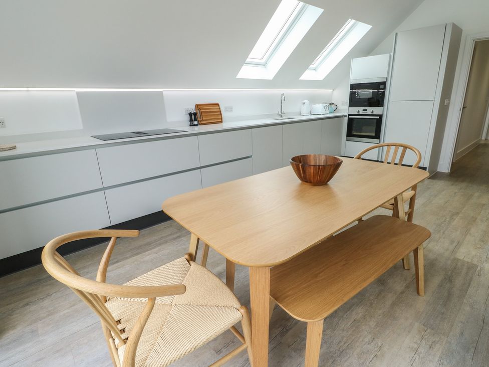 A kitchen with a wooden table and chairs at Glynllifon 7 Marian-glas near Benllech