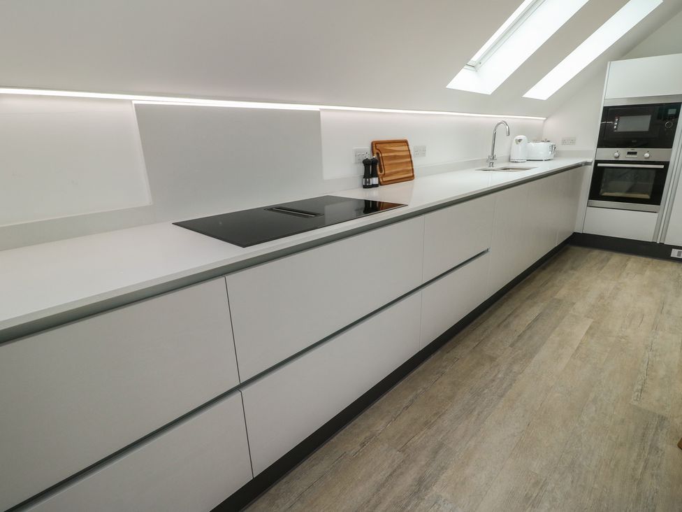 A kitchen with a counter, sink, stove, and oven at Glynllifon 7 Marian-glas near Benllech