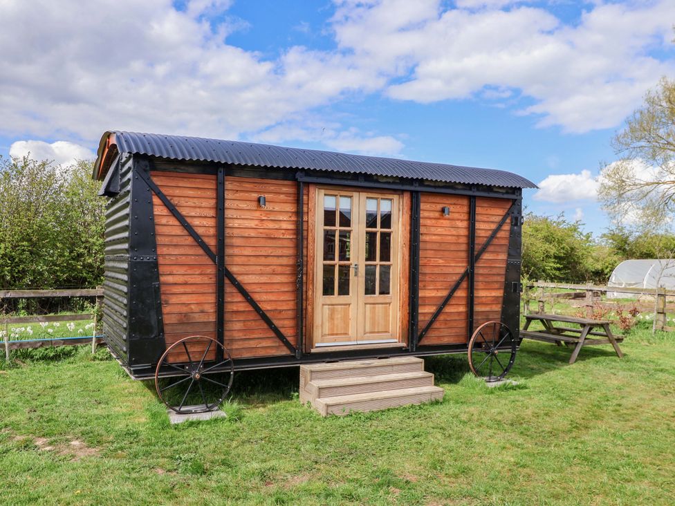 A wooden cabin with double doors and picnic table at The Damselfly in 