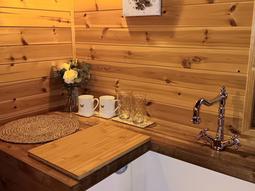 A kitchen corner with a sink, cutting board, mugs, and glasses at The Damselfly Bewholme near Hornsea